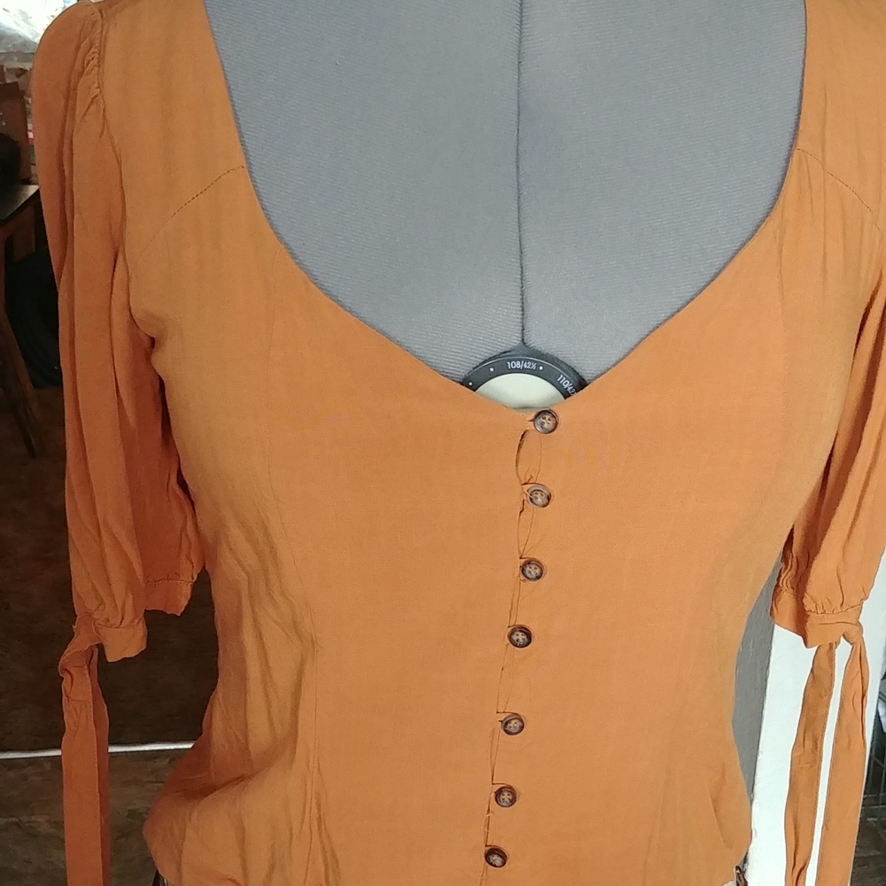 3/4 Sleeve with tie at cuff. Off shoulder halter, button up with honeycomb back.